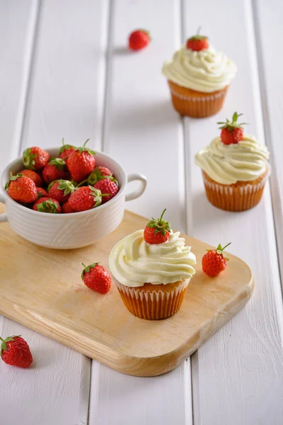 Çilekli lezzetli ve güzel kokulu kekler ve beyaz arka planda yumuşak krema.