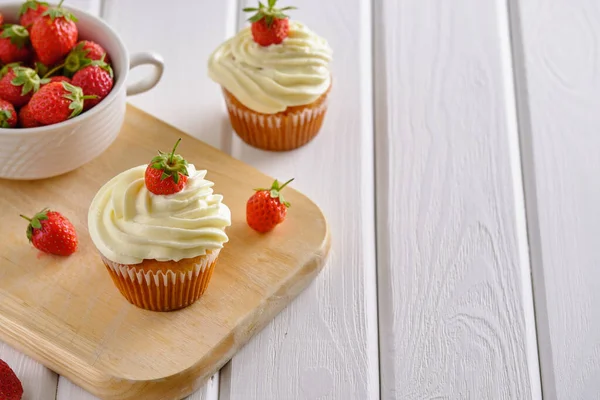 Çilekli lezzetli ve güzel kokulu kekler ve beyaz arka planda yumuşak krema.