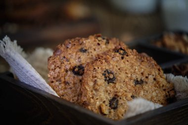 Lezzetli ve lezzetli yulaf ezmeli kurabiyeler fındıklı, kuru üzümlü ve baharatlı eski ahşap masa üzerinde bir fincan sütle.