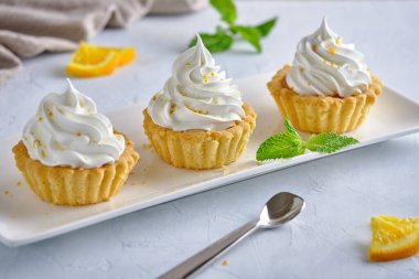 Turuncu reçelli turta ve beyaz tabakta portakal aromalı krema.