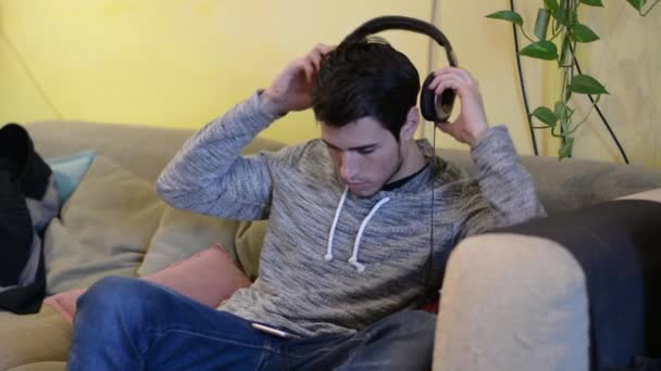 Joven guapo en la cama escuchando música — Vídeos de Stock