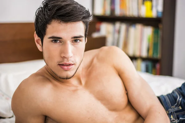 Skjortlös sexig manlig modell som ligger ensam på sin säng — Stockfoto