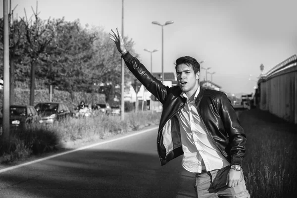 Beau jeune homme, auto-stoppeur en attente sur le bord de la route — Photo