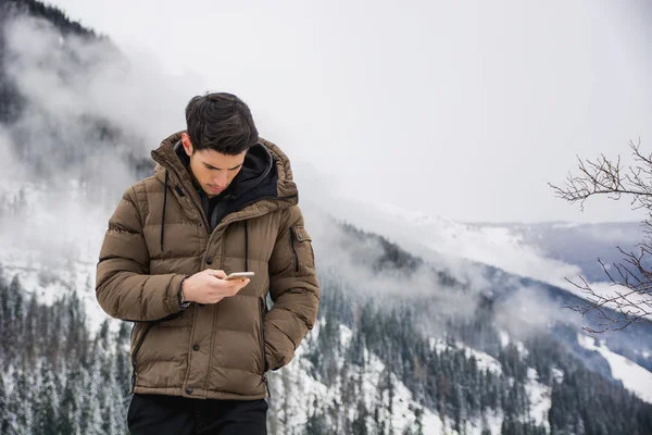 Jonge man in bij mountain gebruik mobiele telefoon — Stockfoto