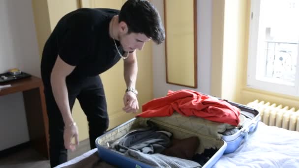 Young man trying to close his suitcase — Stock Video