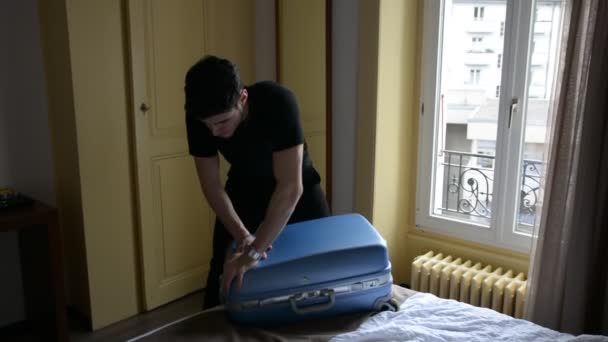 Joven tratando de cerrar su maleta — Vídeo de stock