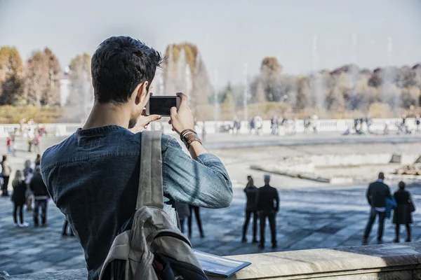 Молодой человек держит путеводитель вне исторического здания — стоковое фото