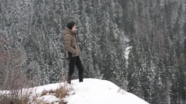 Чоловік у верхньому одязі стоїть у снігу — стокове відео