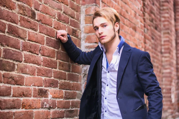 Knappe jongeman tegen bakstenen muur — Stockfoto