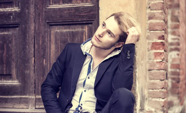 Handsome young man against brick wall — Stock Photo, Image