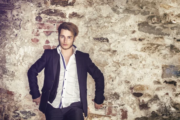 Handsome young man against brick wall — Stock Photo, Image