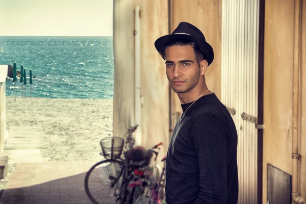 Man in black hat standing near wall while looking at camera — Stock Photo, Image