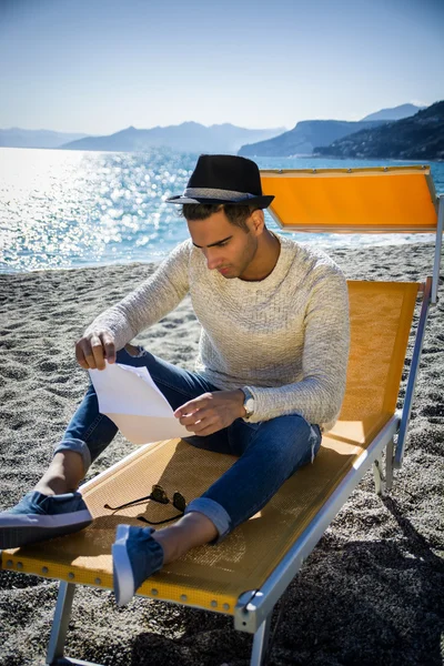 Man zit op de strandstoel tijdens het lezen van de brief — Stockfoto