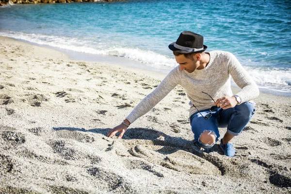 Homem sentado na praia enquanto olhando para longe — Fotografia de Stock