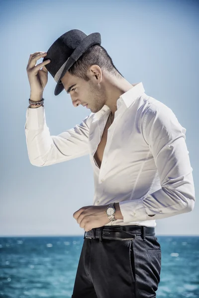 Hombre guapo en camisa blanca y sombrero en la playa —  Fotos de Stock