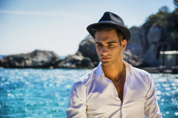 Schöner Mann in weißem Hemd und Hut am Strand — Stockfoto