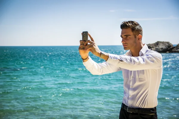 Mladý muž na pláži fotí Selfie — Stock fotografie