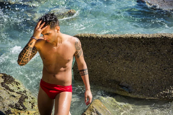 Young man standing in water by sea or ocean shore, — Stock Photo, Image