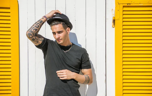 Man in black hat standing against wooden wall — Stock Photo, Image