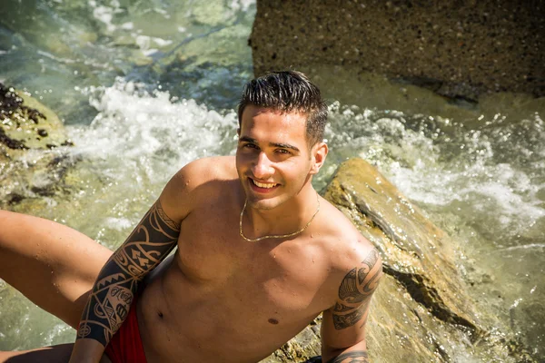 Young man standing in water by sea or ocean shore, — Stock Photo, Image