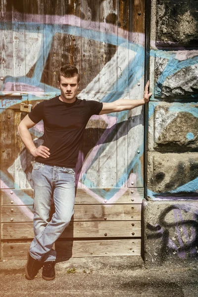 Attractive young man standing against graffiti — Stock Photo, Image