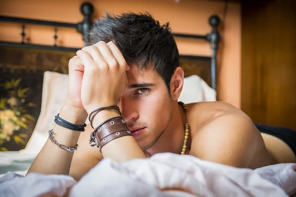 Shirtless sexy male model lying alone on his bed — Stock Photo, Image