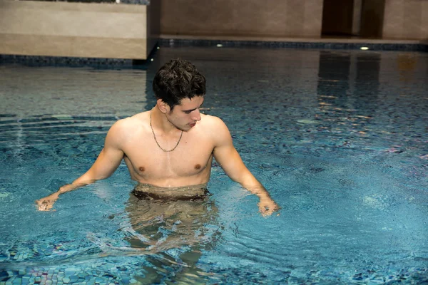 Homem jovem relaxante na piscina — Fotografia de Stock