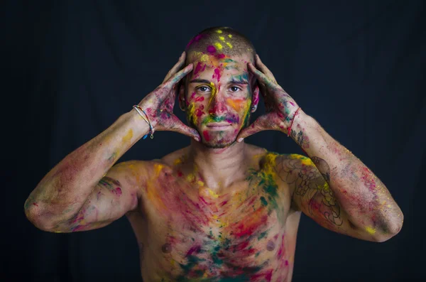 Stilig ung man med skinn alla målade med Holi färger — Stockfoto