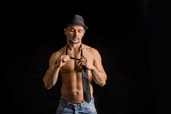 Muscular man wearing jeans, hat and neck-tie — стоковое фото