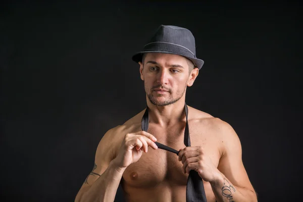 Muscular man wearing jeans, hat and neck-tie — Zdjęcie stockowe