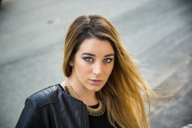 Dışarıda siyah deri ceketli genç bir kadın var.