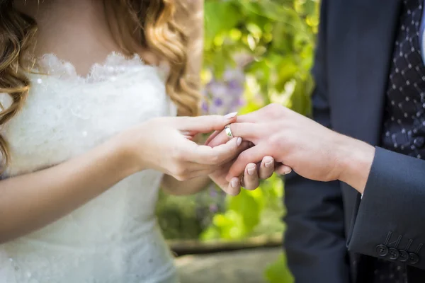 Primer plano de la novia poniendo el anillo de bodas en dedo de novios — Foto de Stock