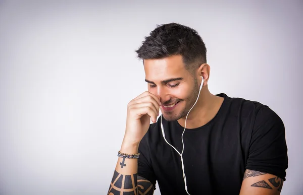 音楽を聴くイヤフォンを持つ若い男 — ストック写真