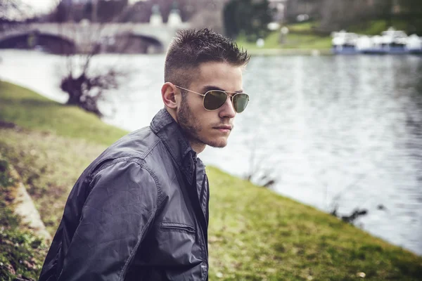 Hombre joven contemplativa sentado al lado del río —  Fotos de Stock