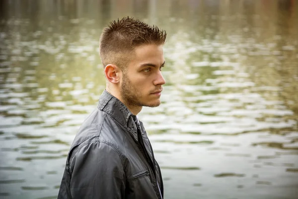 Contemplatieve jonge man die naast de rivier — Stockfoto