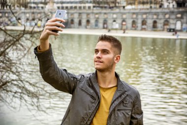 Young man taking selfie beside river