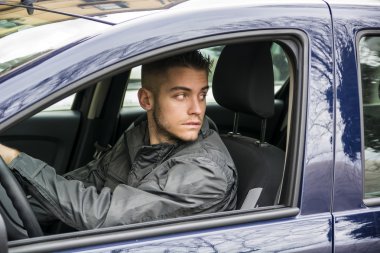 Genç adam araba kullanıyor.