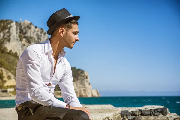 Bonito homem de camisa branca e chapéu na praia — Fotografia de Stock