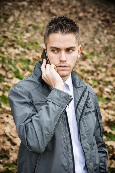 Jeune homme dans le parc en utilisant un téléphone portable — Photo