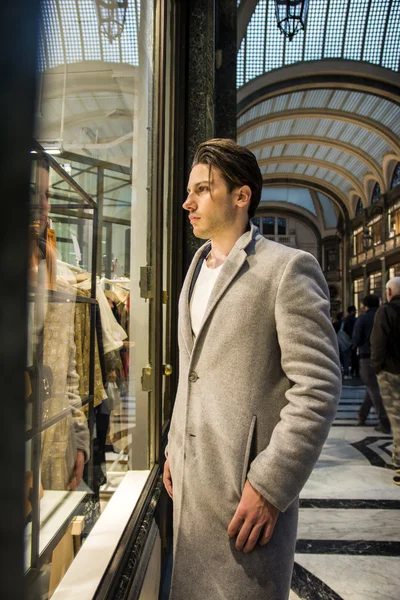 Hombre joven mirando artículos de moda en la ventana de la tienda —  Fotos de Stock