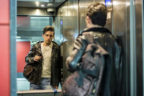 Bonito jovem encostado ao espelho no elevador ou elevador — Fotografia de Stock