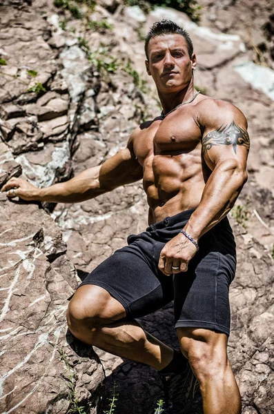 Handsome, muscular, shirless climber climbing rock — Stok fotoğraf