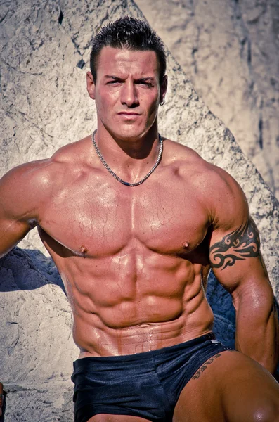 Attractive young muscle man shirtless against white rocks — Stock Photo, Image