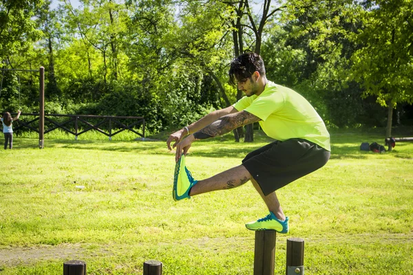 Sportsman balancing in pistol squat on wooden bar — Stock Photo, Image