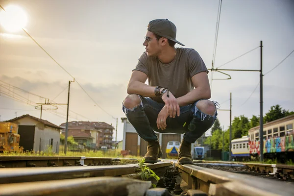 Aantrekkelijke jongeman zittend op de spoorweg — Stockfoto