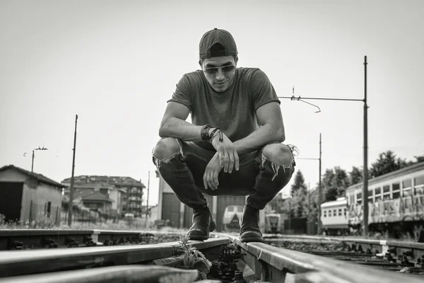Attraktiver junger Mann sitzt auf Eisenbahn — Stockfoto
