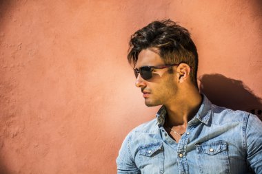 Turuncu duvara oturan yakışıklı adam