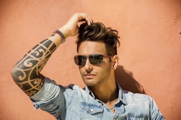 Hombre guapo sentado contra la pared naranja — Foto de Stock