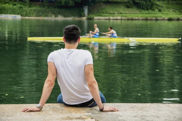 Contemplative young man sitting beside river — Stock Photo, Image