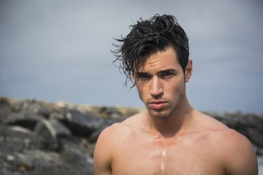 Okyanus kıyısında suda duran genç üstsüz atletik adam.